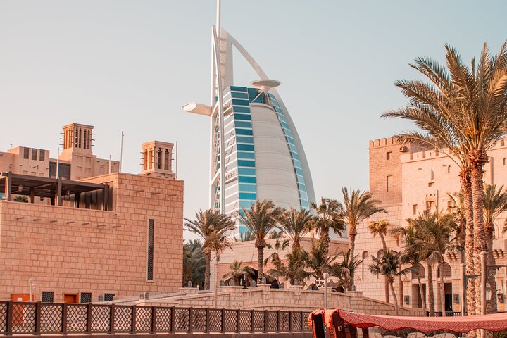 Experience the blend of modern luxury and traditional charm as you explore the striking Burj Al Arab against a backdrop of cultural landmarks and lush palm trees.